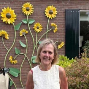 Opdrachtgever Ria bij de monumentale RVS wandsculptuur met zonnebloemen aan haar woning.
