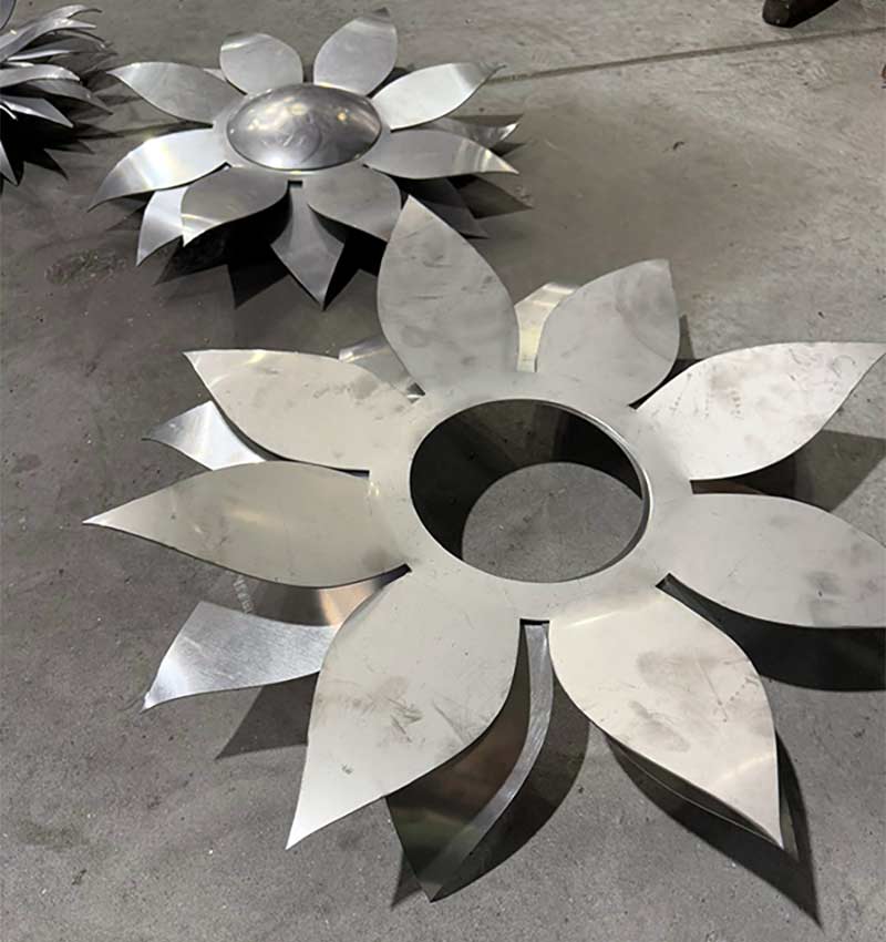 two assembled stainless steel sunflowers with shaped petals for a monumental wall sculpture